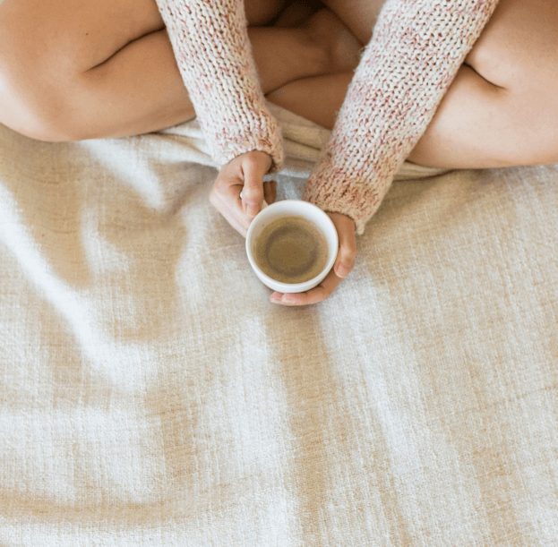 woman holding cup of coffee in bed